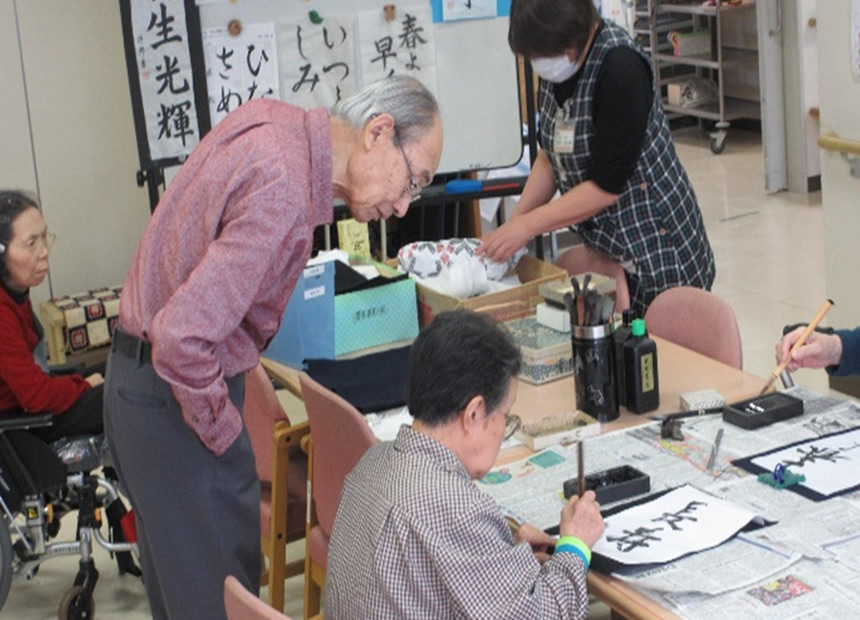 書道を得意としている方が書初めを行った際に他の利用者様に教えてあげている姿です